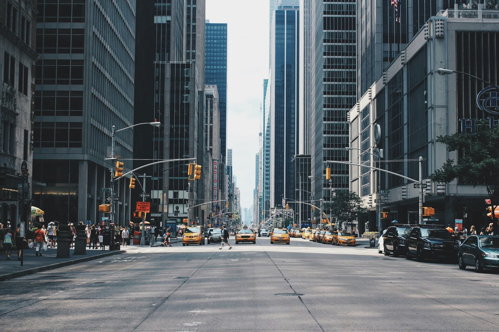 Busy city street with taxis and pedestrians between tall buildings