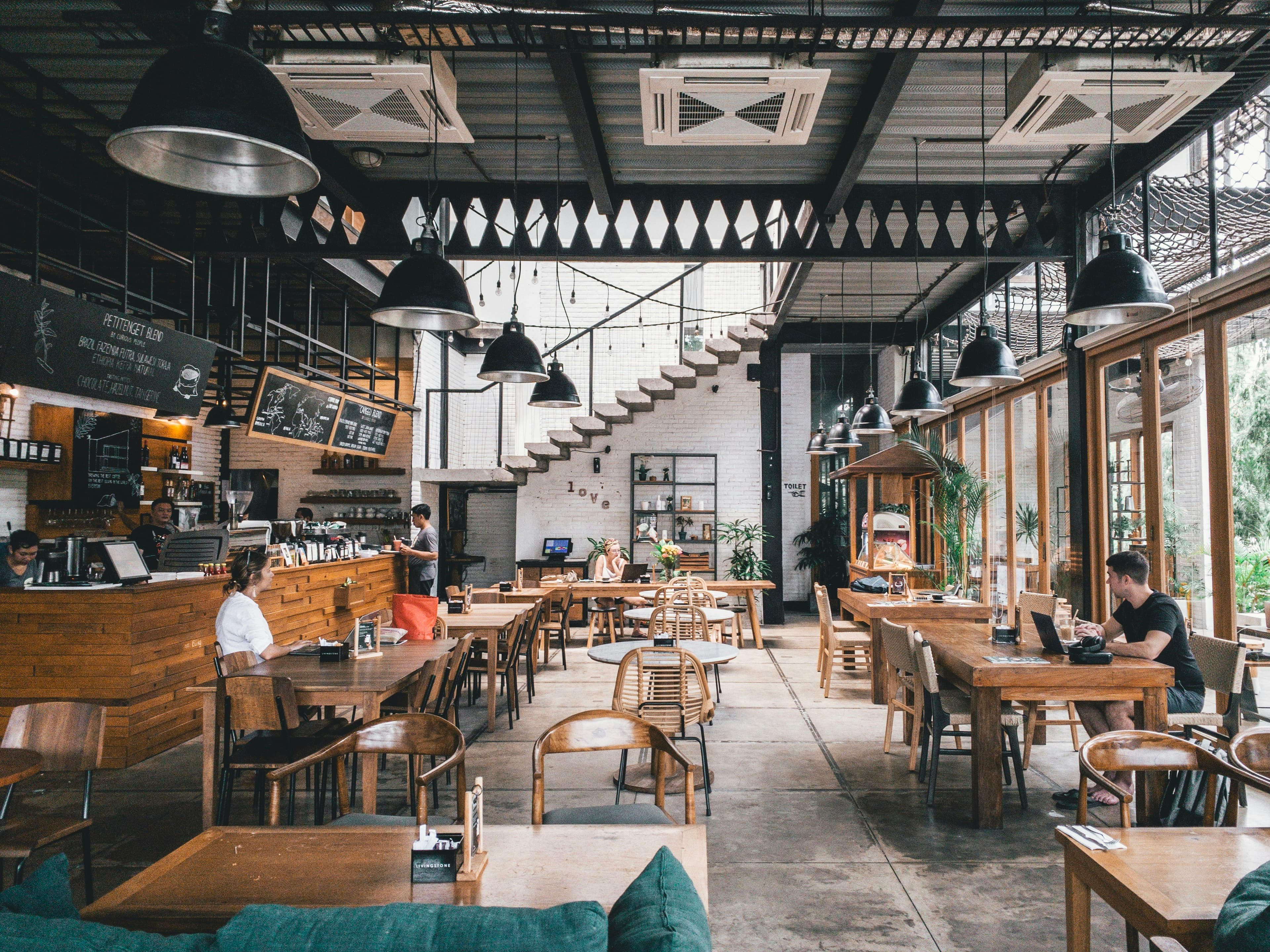 Warm industrial-style cafe interior with pendant lighting and people at tables